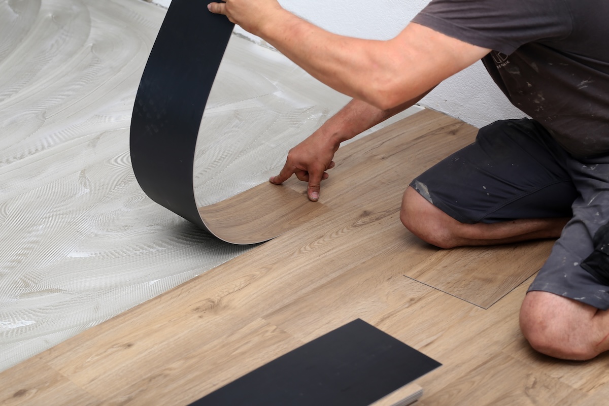 The worker installing new vinyl tile floor.